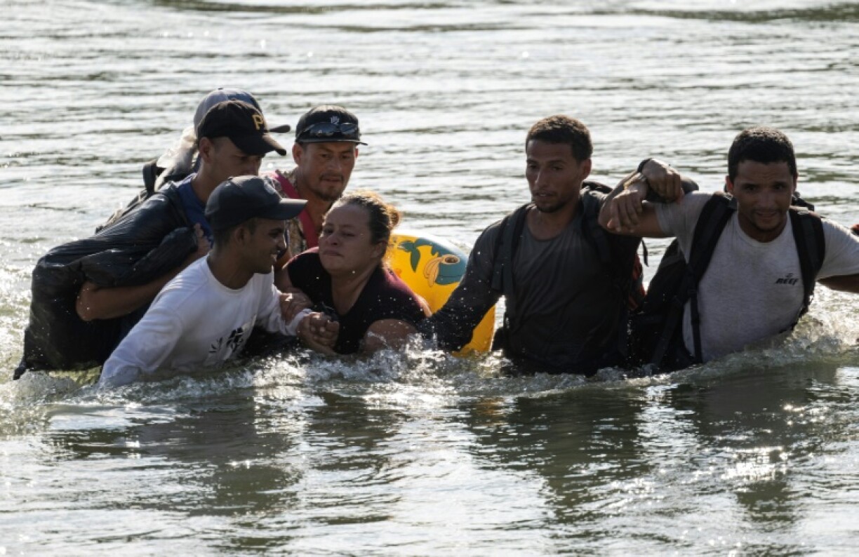 Un groupe de migrants aide Maria Argentina, 32 ans, originaire du Honduras, à traverser le Rio Grande pour rejoindre les Etats-Unis, le 24 septembre 2023