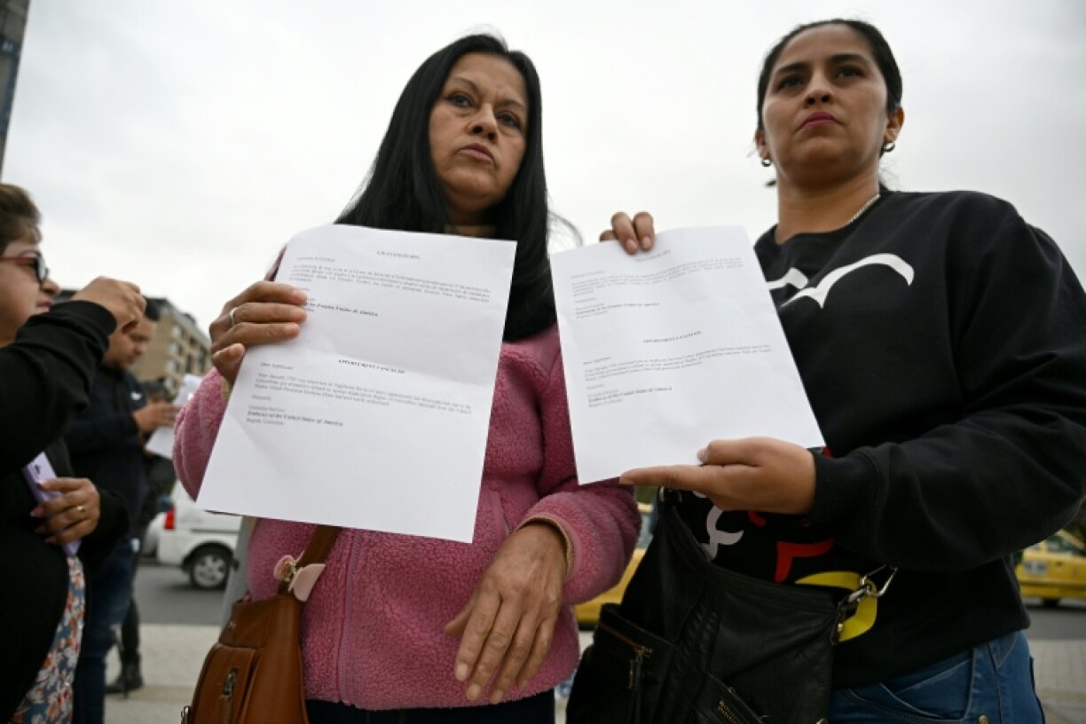 Women hold letters from the US embassy after their visa appointments was cancelled in Bogota