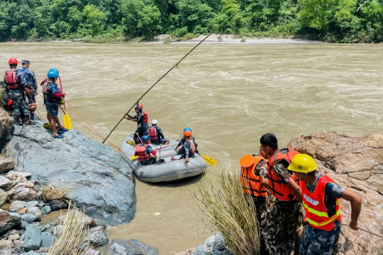 Des membres de la police armée recherchent des survivants dans la rivière Trishuli après un glissement de terrain qui a emporté deux bus, le 13 juillet 2024 à Simaltar, au Népal