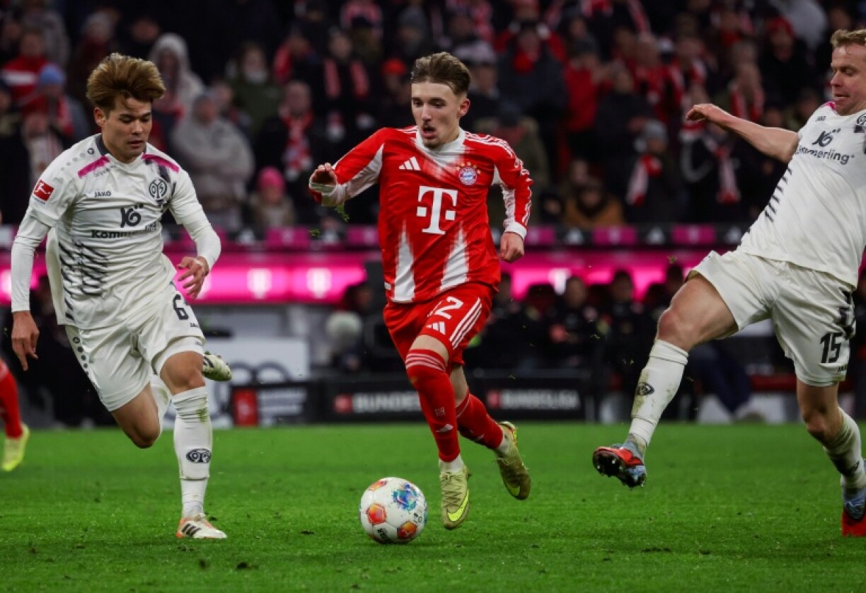 Le Bavarois Lennart Karl (C) au milieu des joueurs de Mayence Lennard Maloney (D) et Kaishu Sano lors du match nul concédé à domicile 2-2, le 14 décembre 2025 à Munich