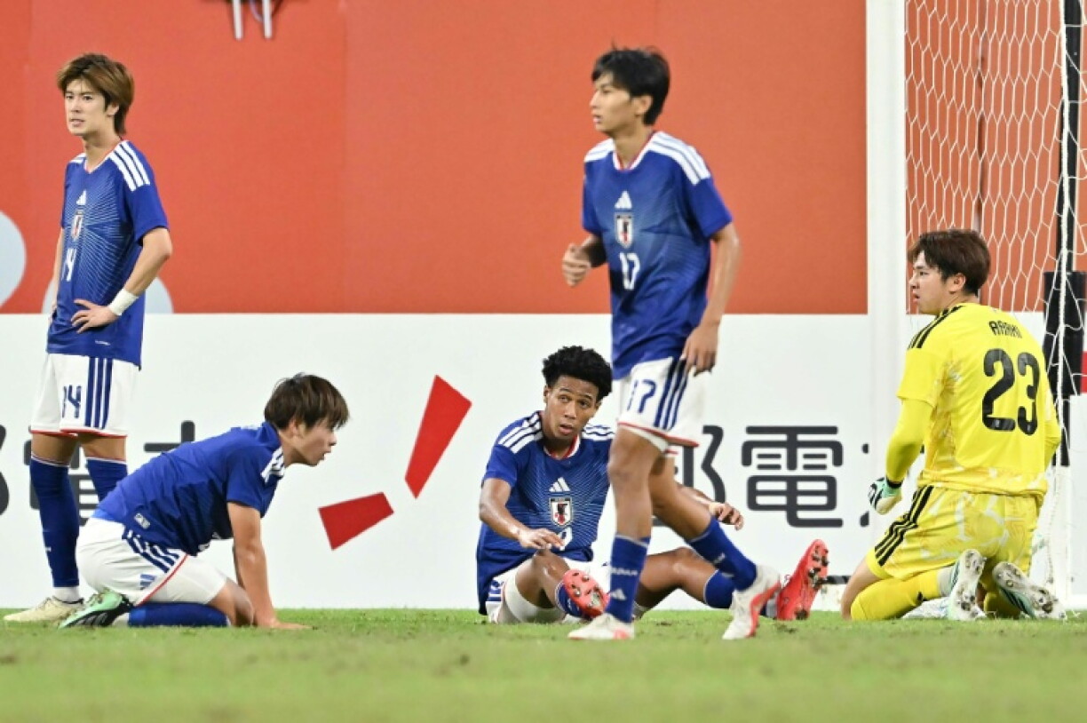 Japan's goalkeeper Rui Araki (R) reacts next to teammates after conceding the only goal of the game