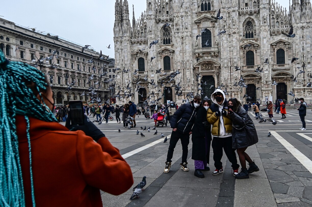Tourists wearing protective masks pose for a picture in front of the Duomo of Milan on January 3, 2022. The use of FFP2 masks in transport, stadiums, movie theatres, museums and sporting events is now mandatory in Italy. Wearing a mask outdoors was already mandatory since 23 December.