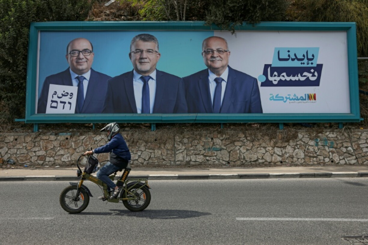 A man rides his motorcycle past an electoral billboard for the Arab-led Joint List political alliance in Israel's northern city of Nazareth on October 21, 2026.
