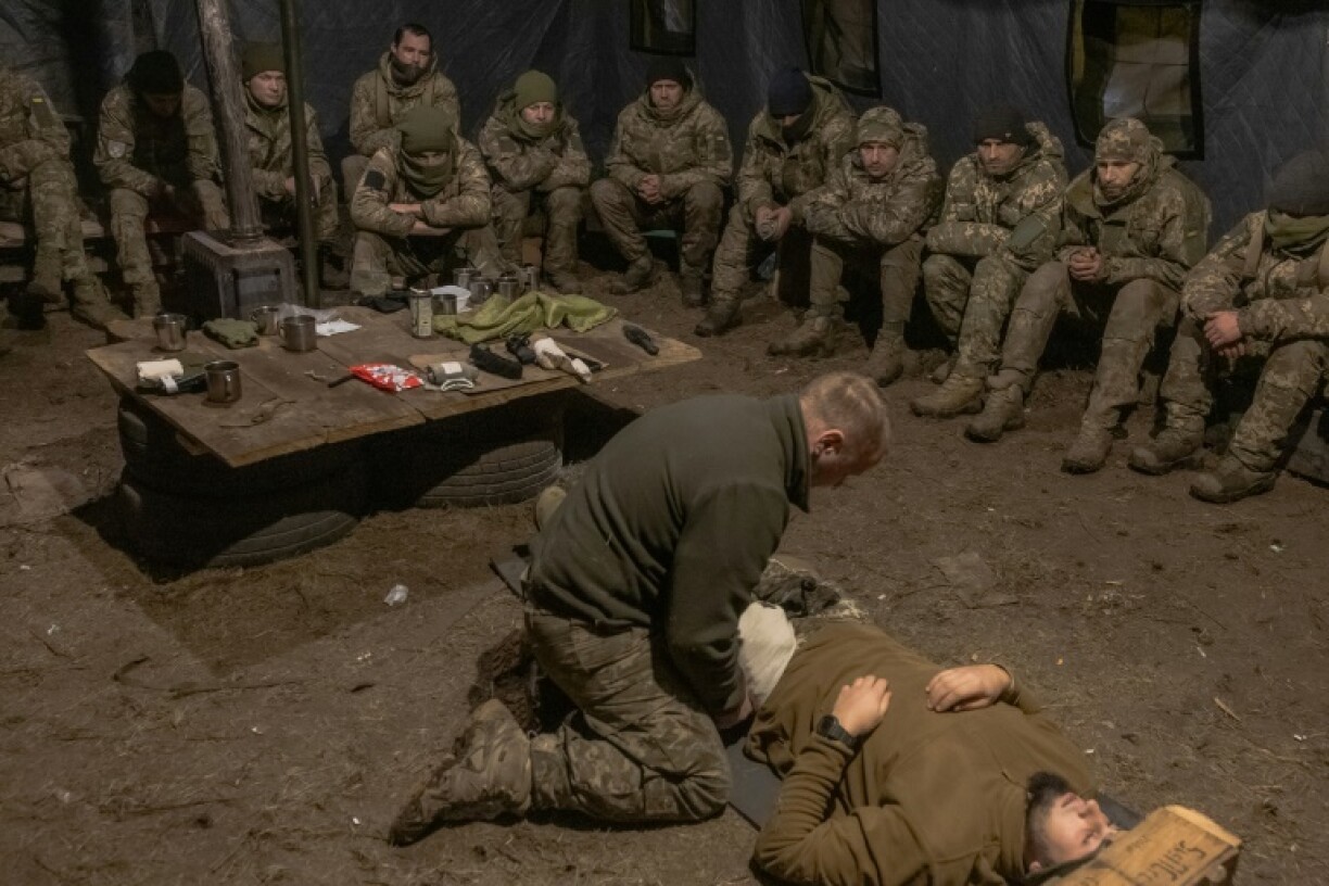 Un soldat ukrainien est soigné devant ses collègues rassemblés sous une tente, dans l'est de l'Ukraine le 12 décembre 2024.