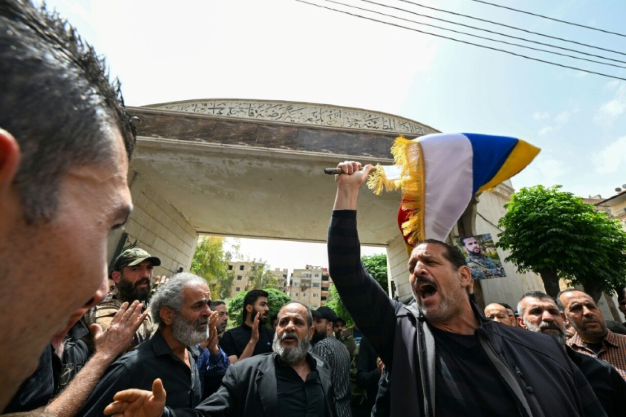 Members of Syria's Druze community wave flags and chant slogans during the funeral of people killed during clashes with Syrian security forces on April 30, 2025