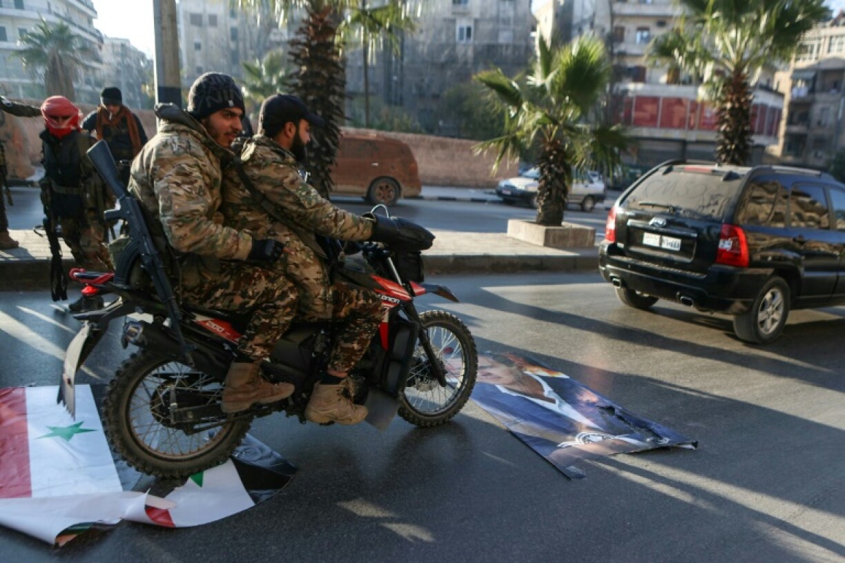 Anti-regime fighters in the centre of Aleppo, Syria's second city, ride over a picture of President Bashar al-Assad