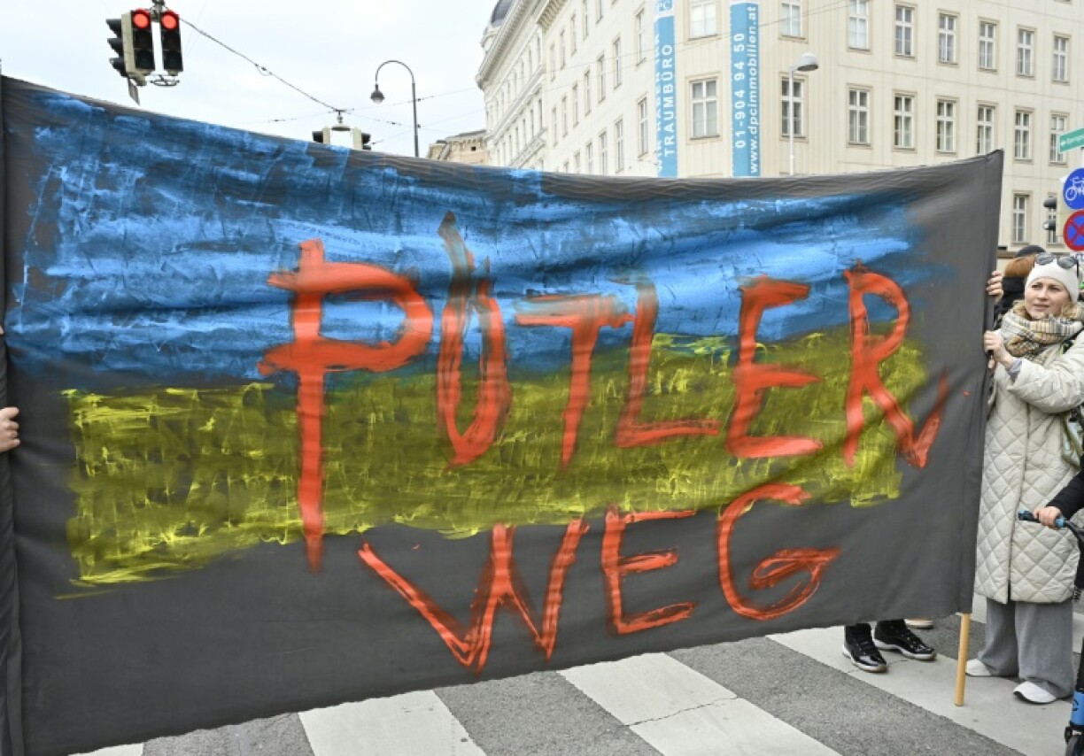 Des manifestants à Vienne avec une banderole comparant le président russe Vladimir Poutine à Hitler lors d'une manifestation contre l'invasion de l'Ukraine, le 26 février 2022