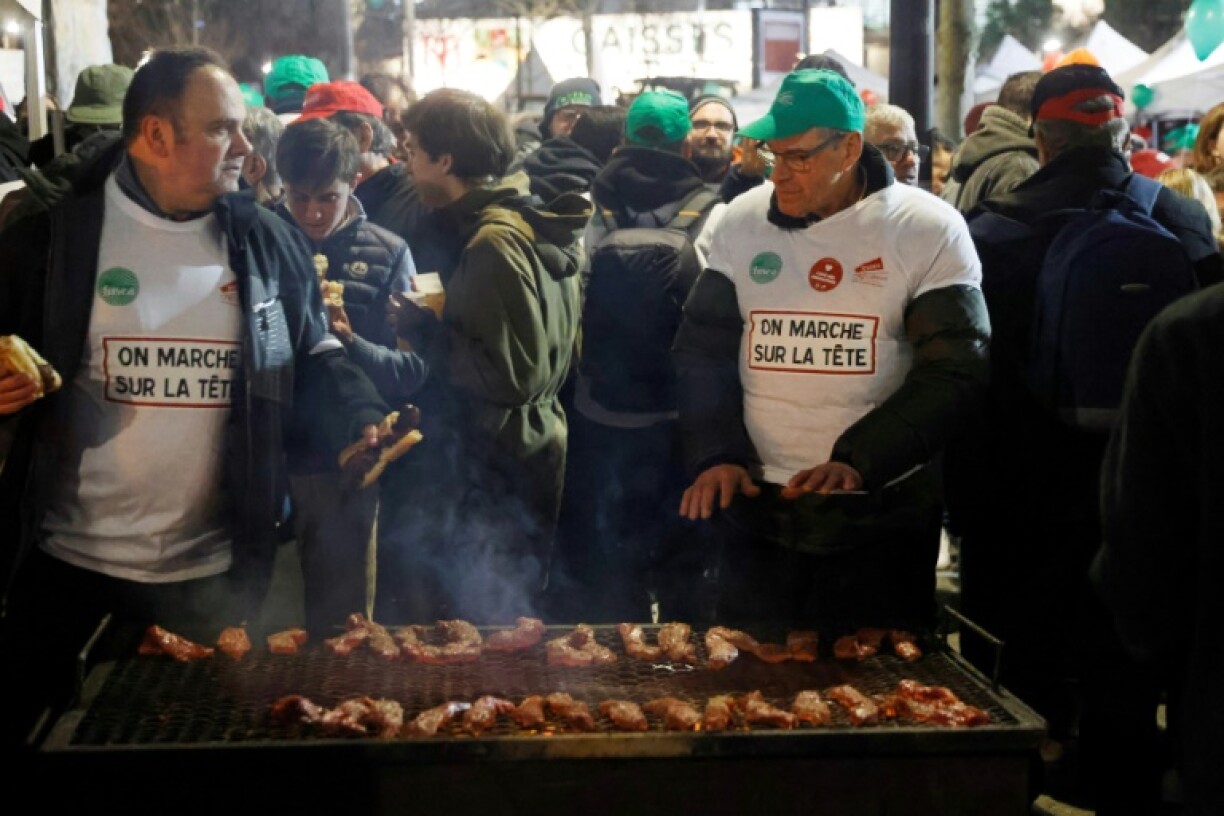 Des agriculteurs préparent de la nourriture lors d'un rassemblement près de la porte de Versailles, le 23 février 2024 à Paris
