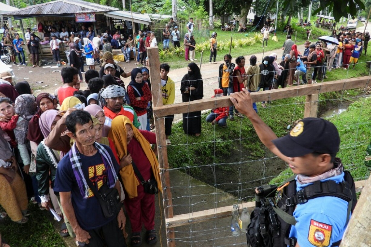 A police officer stands guard as voters up outside a polling station in Panamao town, Sulu province, in the southern Philippines