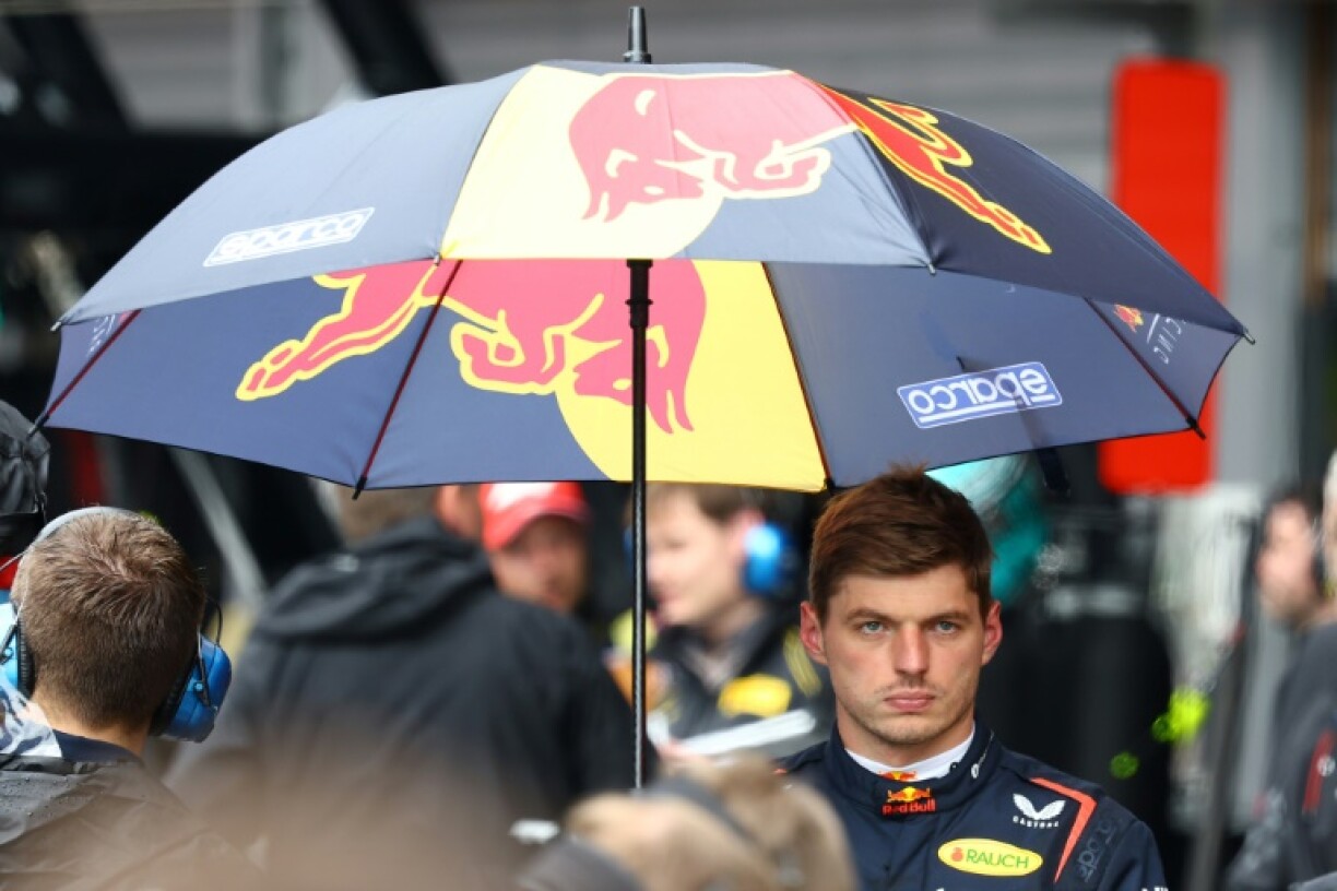 Max Verstappen takes refuge under an umbrella as rain delayed Belgian Grand Prix start