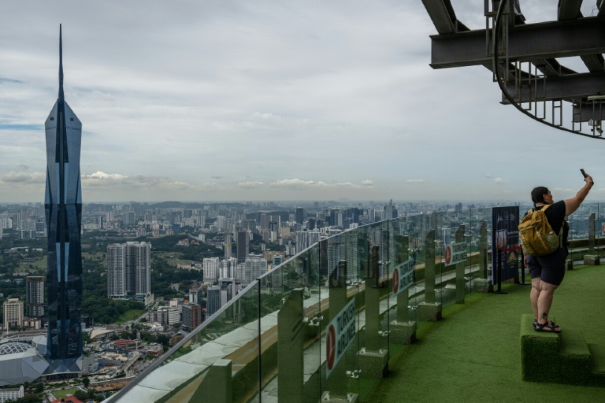 A tourist takes a selfie with the city skyline seen in the background as haze conditions due to Indonesian wildfires improve in Kuala Lumpur on October 26, 2026