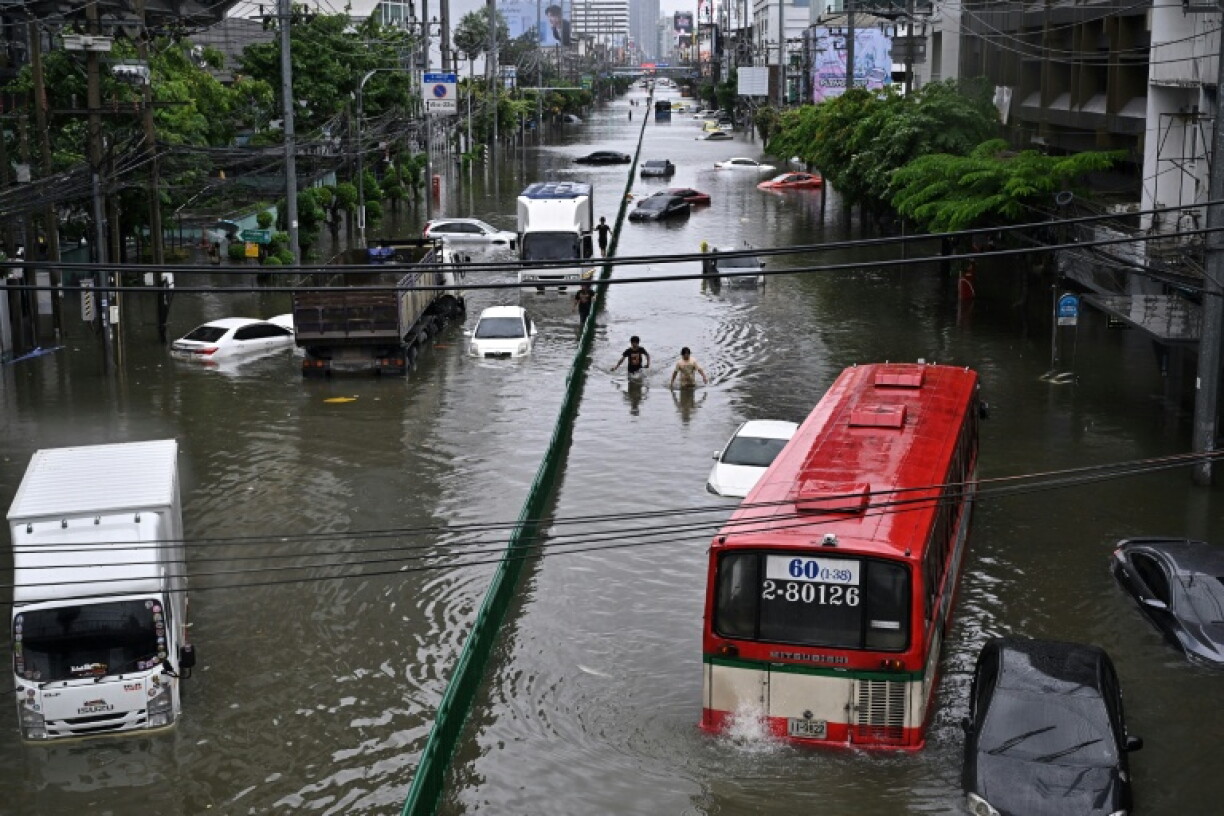 People walk along a flooded Petchaburi road in Bangkok