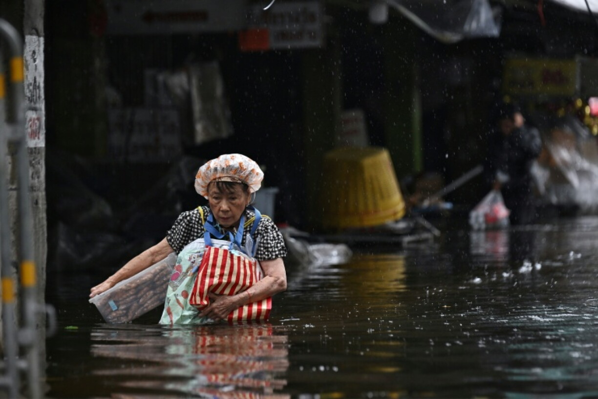 Residents carry supplies while navigating floodwater in Bang Kapi district in Bangkok