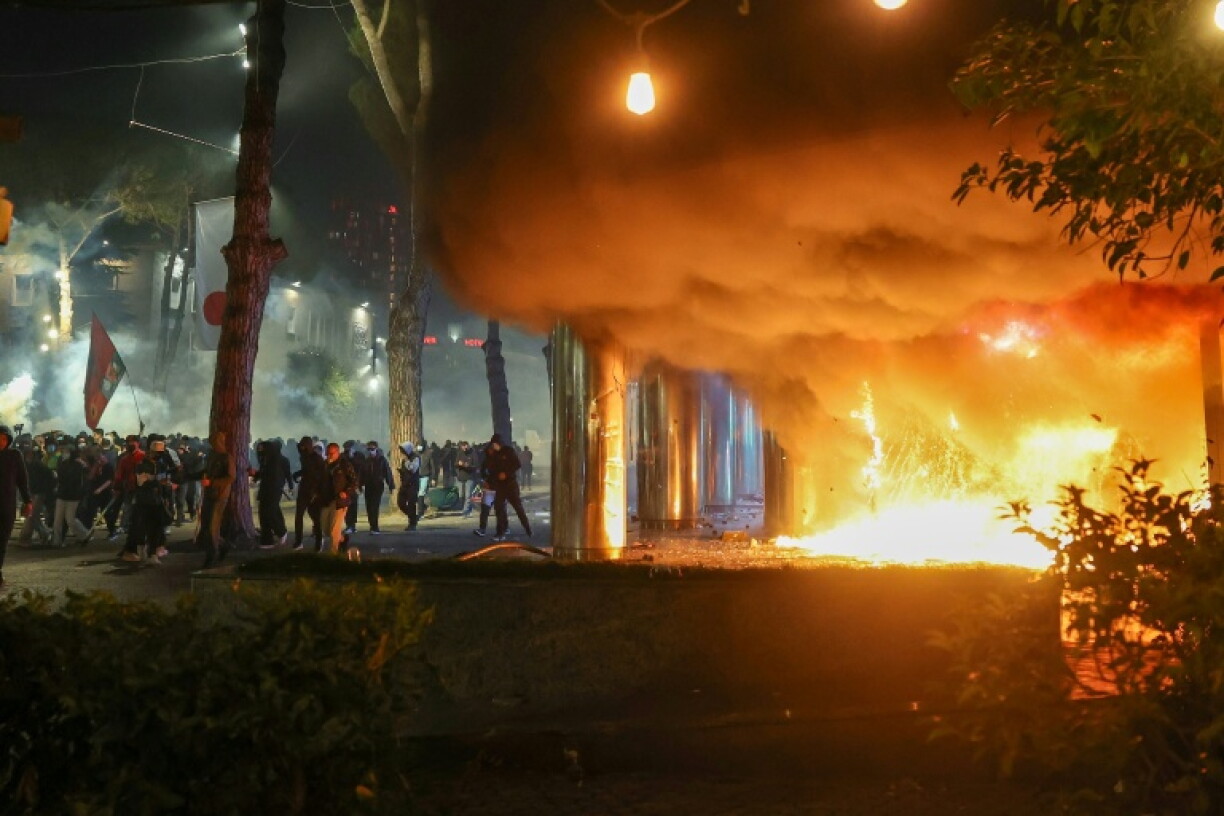Smoke billows from a fire near a group of protesters during clashes with riot police in central Tirana on October 14, 2026, as violence erupted for a second consecutive day during demonstrations demanding the resignation of Albanian Prime Minister Edi Rama and better education. The renewed clashes followed violence the previous day, when protesters threw stones, smashed windows at the Education Ministry, tore down a fence and set rubbish bins on fire.