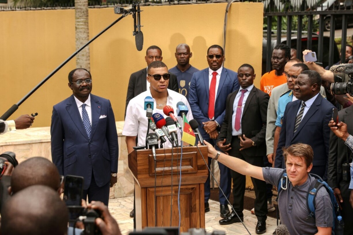 L'attaquant vedette du Paris Saint-Germain et de l'équipe de France de football Kylian Mbappé (c.) s'exprime lors d'une conférence de presse avec le ministre camerounais des sports et de l'éducation physique Narcisse Mouelle Kombi à Yaoundé le 7 juillet 2023 lors d'une visite du village de son père