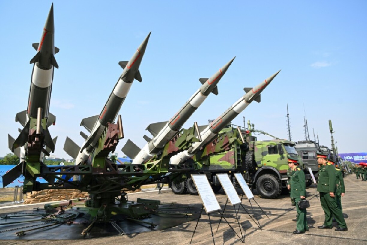 Vietnamese military officials look at an anti-aircraft missile launcher and ammunition during a defence expo in Hanoi