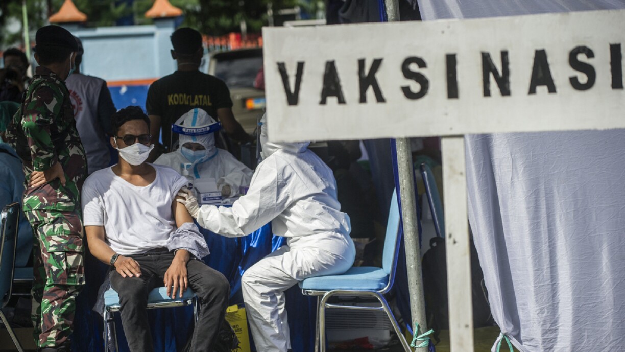 A health worker administers a dose of the Sinovac Covid-19 vaccine during a mass vaccination at a housing area in Surabaya on June 24, 2021.