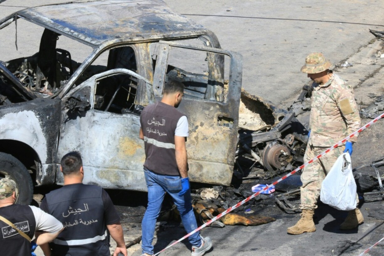 A Lebanese army soldier and forensics experts inspect a burnt-out vehicle in Braiqaa, in south Lebanon's Nabatiyeh district, after what the military called a munitions blast