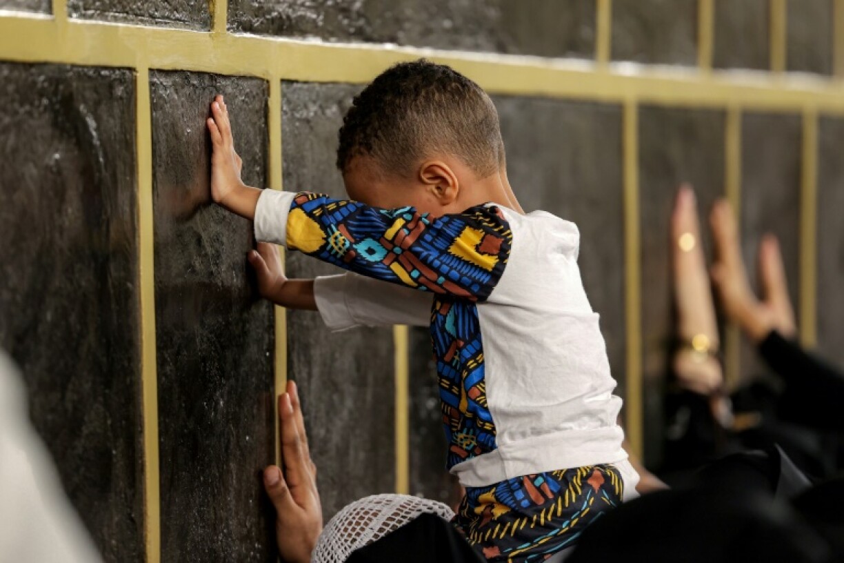 A young boy is lifted up to touch the Kaaba, Islam's holiest shrine, alongside other worshippers at the Grand Mosque complex in the holy city of Mecca