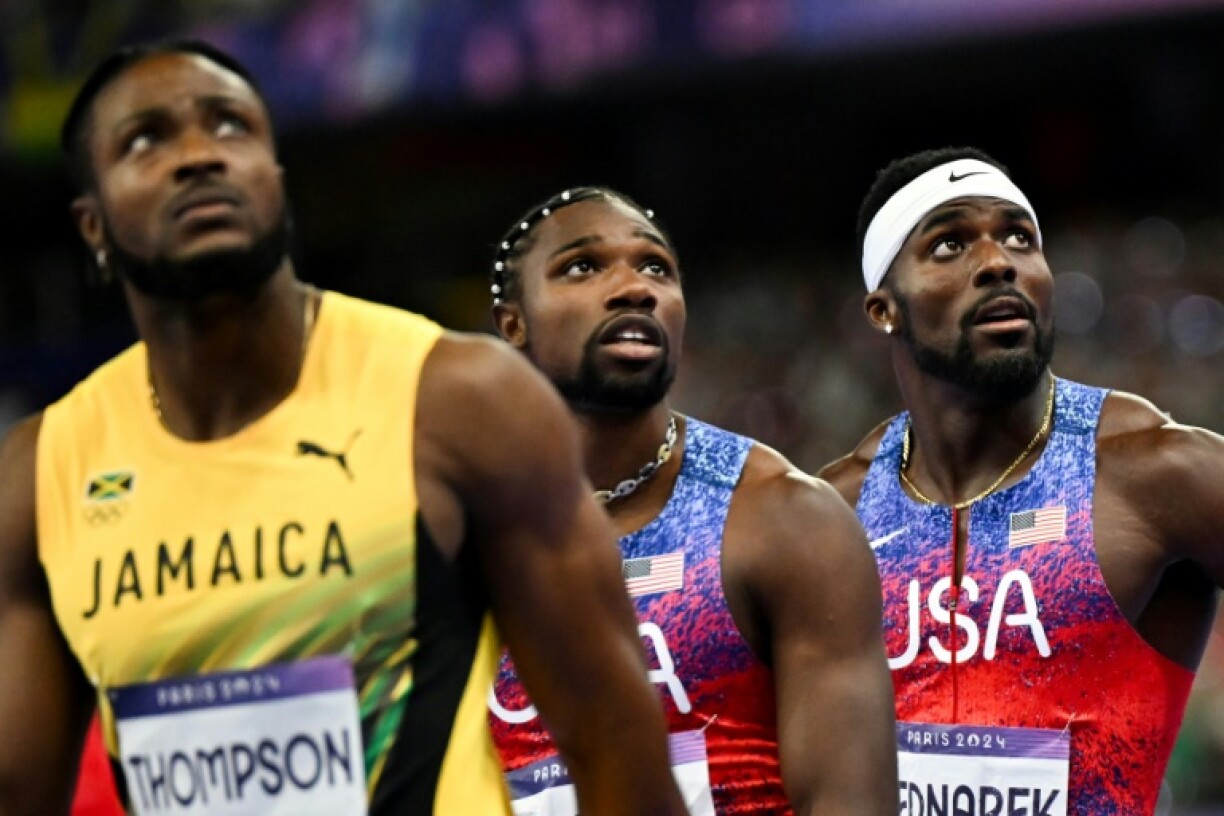Jamaica's Kishane Thompson (L), US' Noah Lyles and US' Kenneth Bednarek (R) react after crossing the finish line in the Olympic men's 100m final