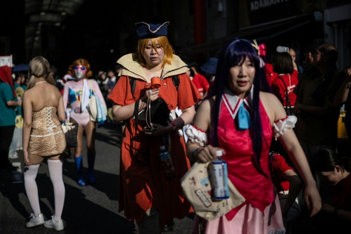 Une personne déguisée utilise un ventilateur portable pour se rafraîchir dans la rue, lors de la deuxième journée du World Cosplay Summit 2026 à Nagoya, le 1er août 2026