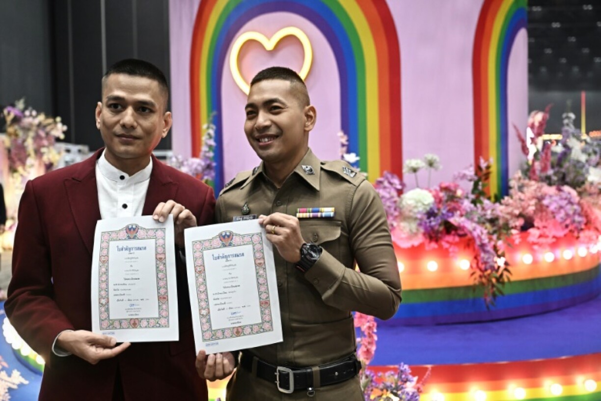 A couple poses with their certificates at the marriage registration event at Paragon shopping mall in Bangkok
