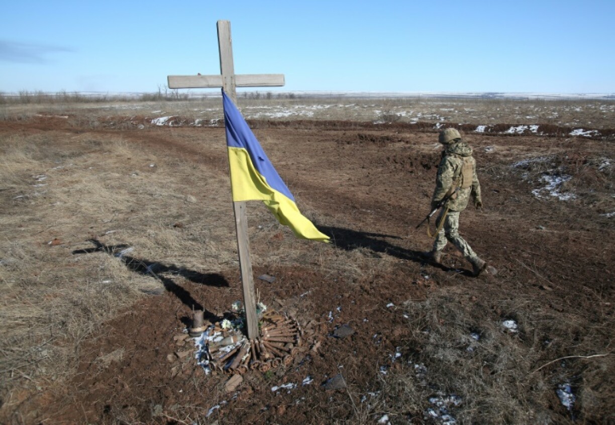 Un soldat ukrainien passe à côté d'un mémorial de fortune à Svetlodarsk, près de Donetsk, en Ukraine, le 12 mars 2022