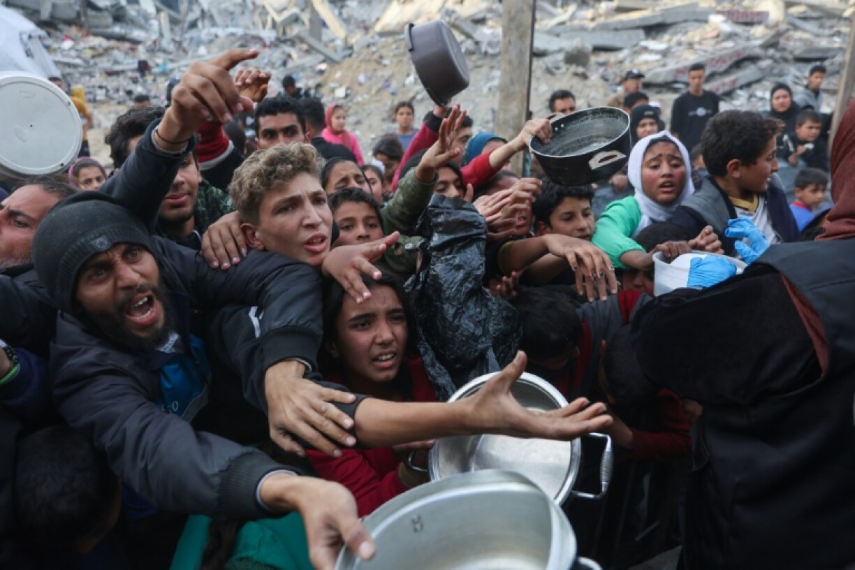 Displaced Palestinian children push into a queue to get a portion of cooked food from a charity kitchen in Beit Lahia, northern Gaza, ahead of the iftar fast-breaking meal during Ramadan