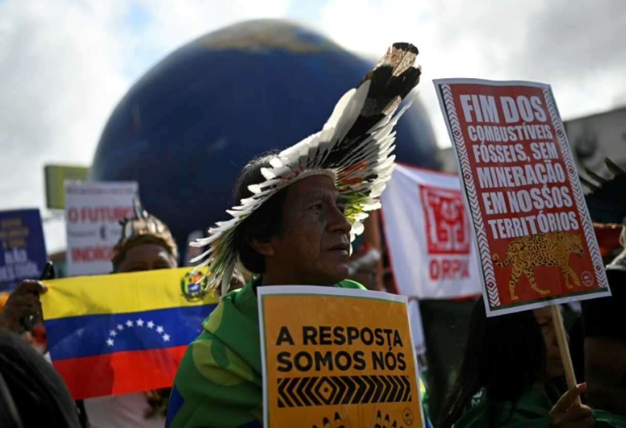 Indigenous people hold signs reading