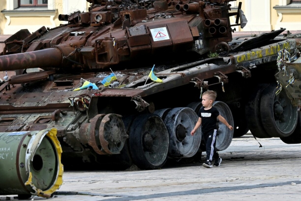 A boy walks past a destroyed tank at an open air exhibition of destroyed Russian military equipment in Kyiv on August 13, 2025, amid the Russian invasion of Ukraine