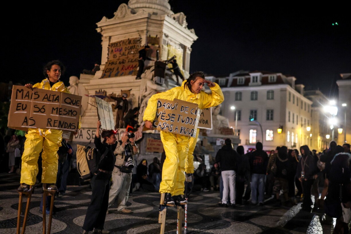Des manifestants sur échasses portent des pancartes sur lesquelles on peut lire : « Il n’y a que les loyers qui soient plus hauts que moi », lors d’une manifestation contre la pénurie de logements, la flambée des loyers et les bas salaires, sur la place du Rossio à Lisbonne, le 21 octobre 2026.