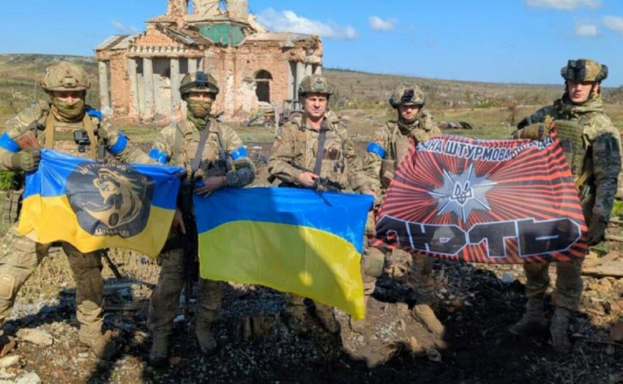 Photo diffusée par Andriy Yermak, chef de cabinet du président ukrainien, le 17 septembre 2023 , montrant des soldats ukrainiens avec des drapeaux nationaux devant un bâtiment détruit dans le village de Klichtchiïvka, dans la région de Donetsk