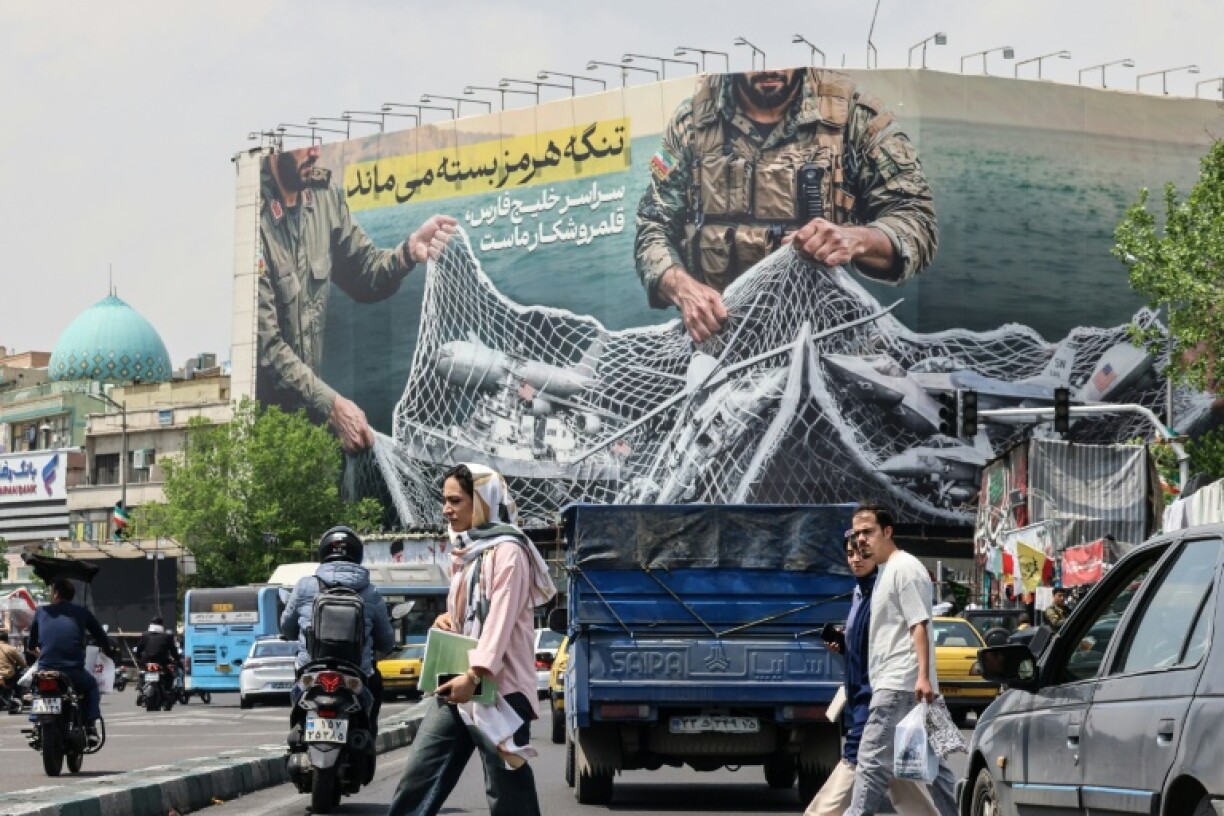 Des Iraniens passent devant un panneau d'affichage géant indiquant "Le détroit d'Ormuz reste fermé" sur la place de la Révolution à Téhéran, le 22 avril 2026