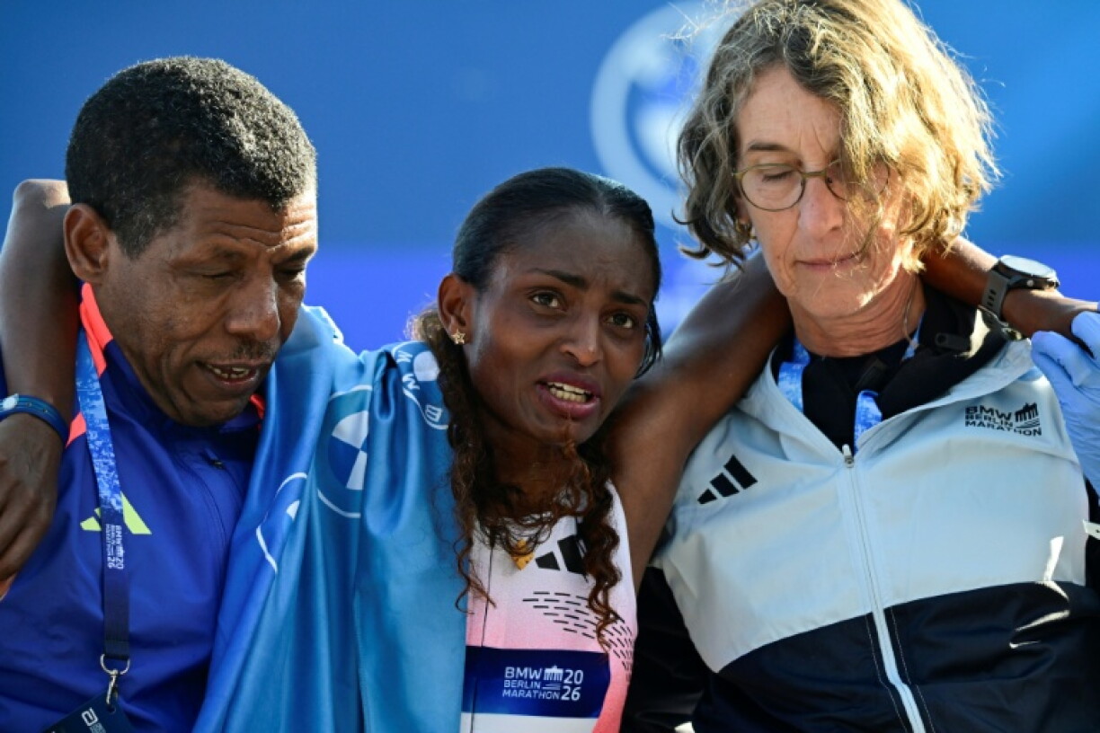 Ethiopia's Tigst Assefa (C) is helped off the track after winning the 2026 Berlin Marathon
