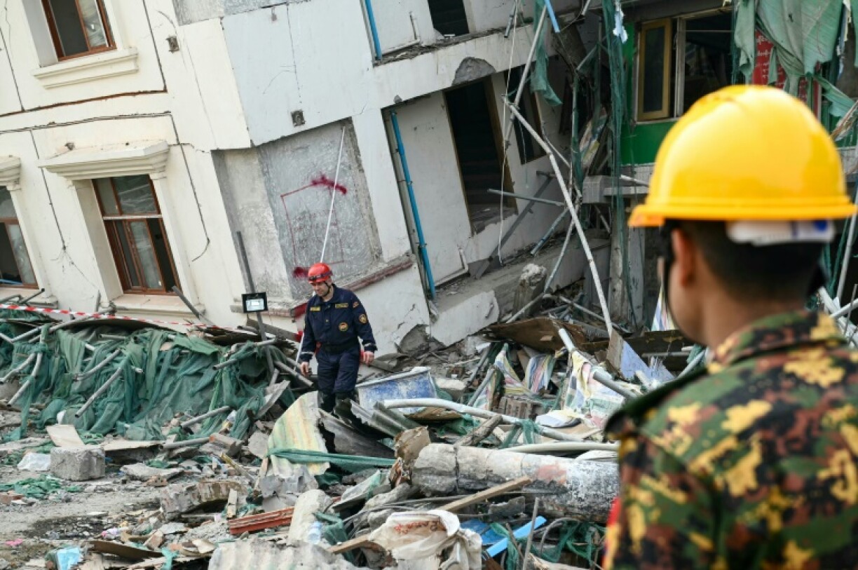 A member of a Belarus' rescue team walks amid the debris past a collapsed building in Mandalay on April 2, 2025