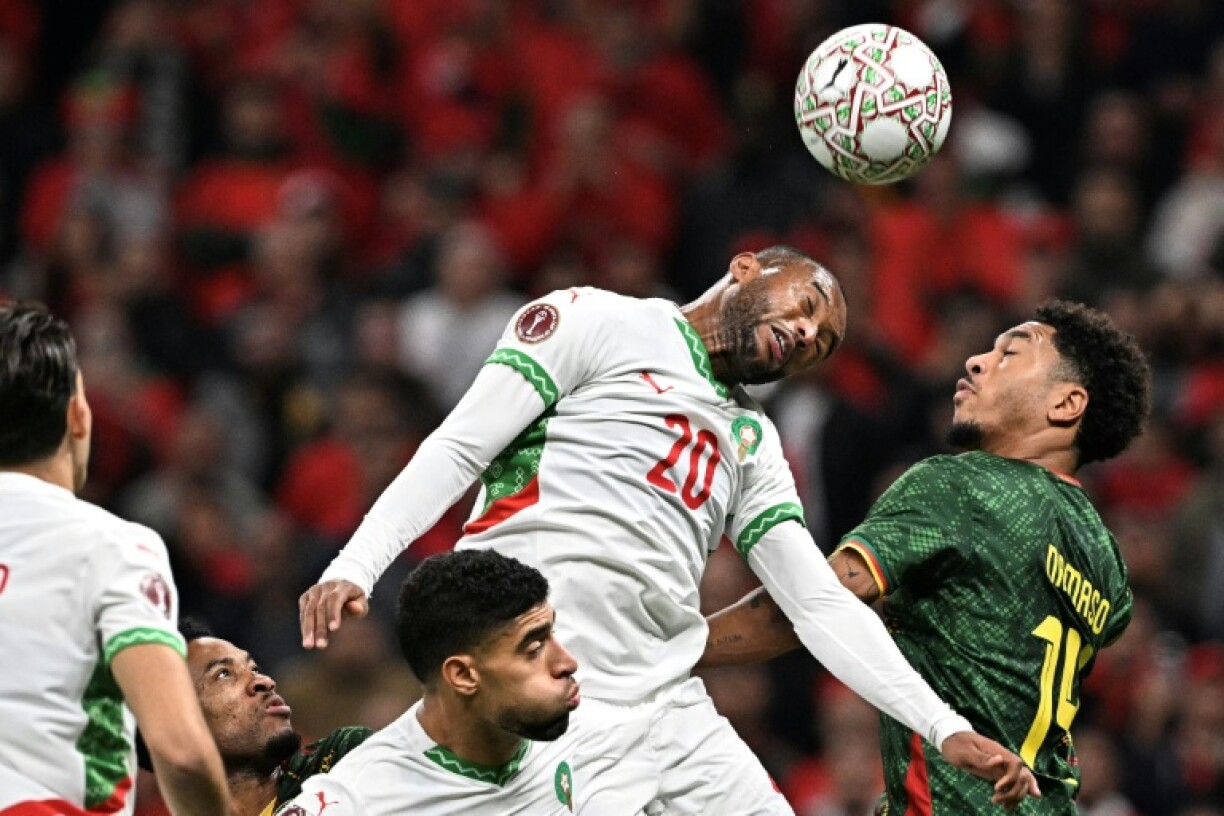 L'attaquant marocain Ayoub El Kaabi (C) reprend le ballon de la tête devant le défenseur camerounais Danny Namaso (D), en quart de finale de la CAN, le 9 janvier 2026 à Rabat