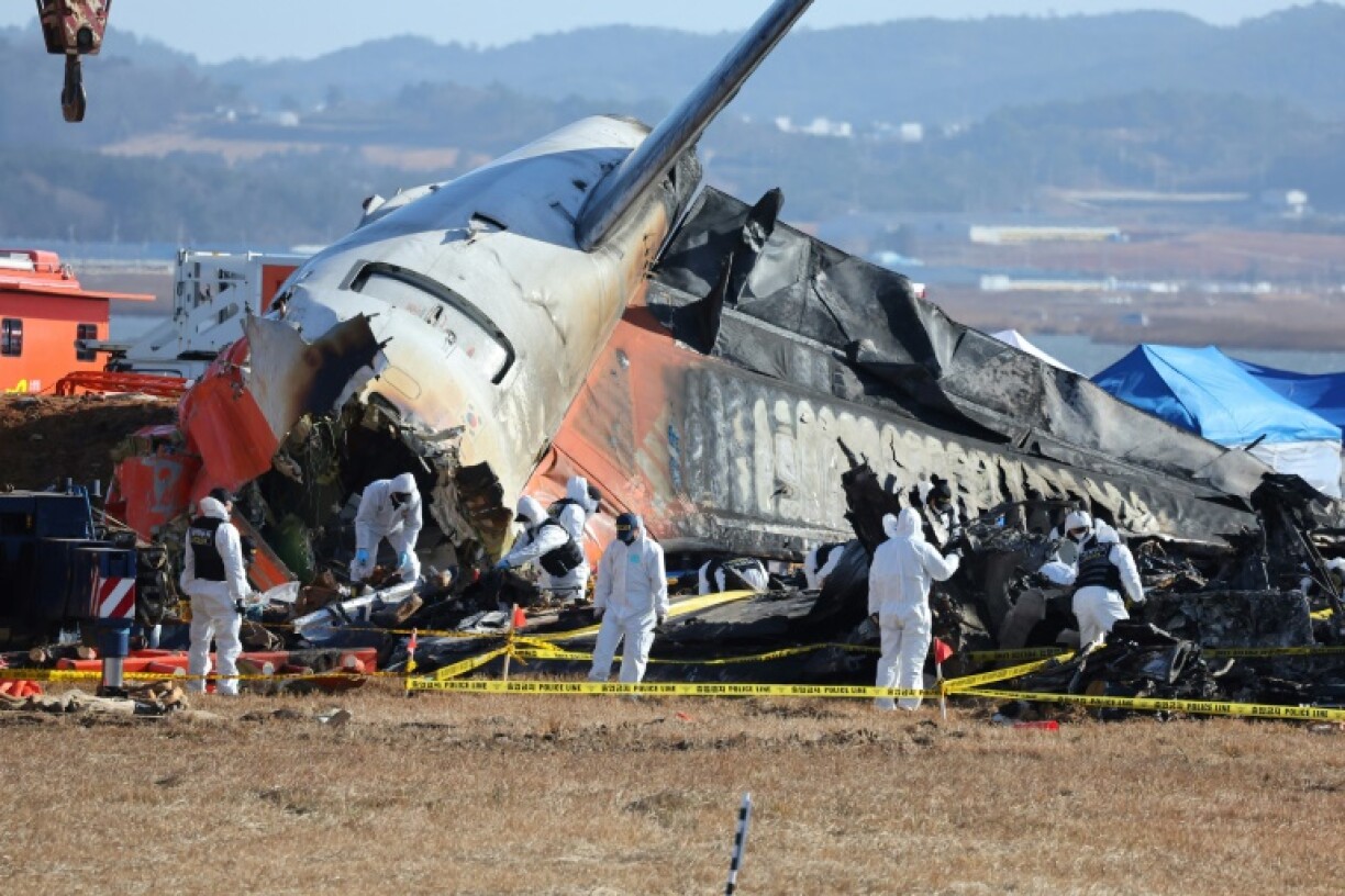 Police forensics personnel and National Bureau of Investigation officials work at the scene where a Jeju Air Boeing 737-800 aircraft crashed and burst into flames at Muan International Airport in Muan
