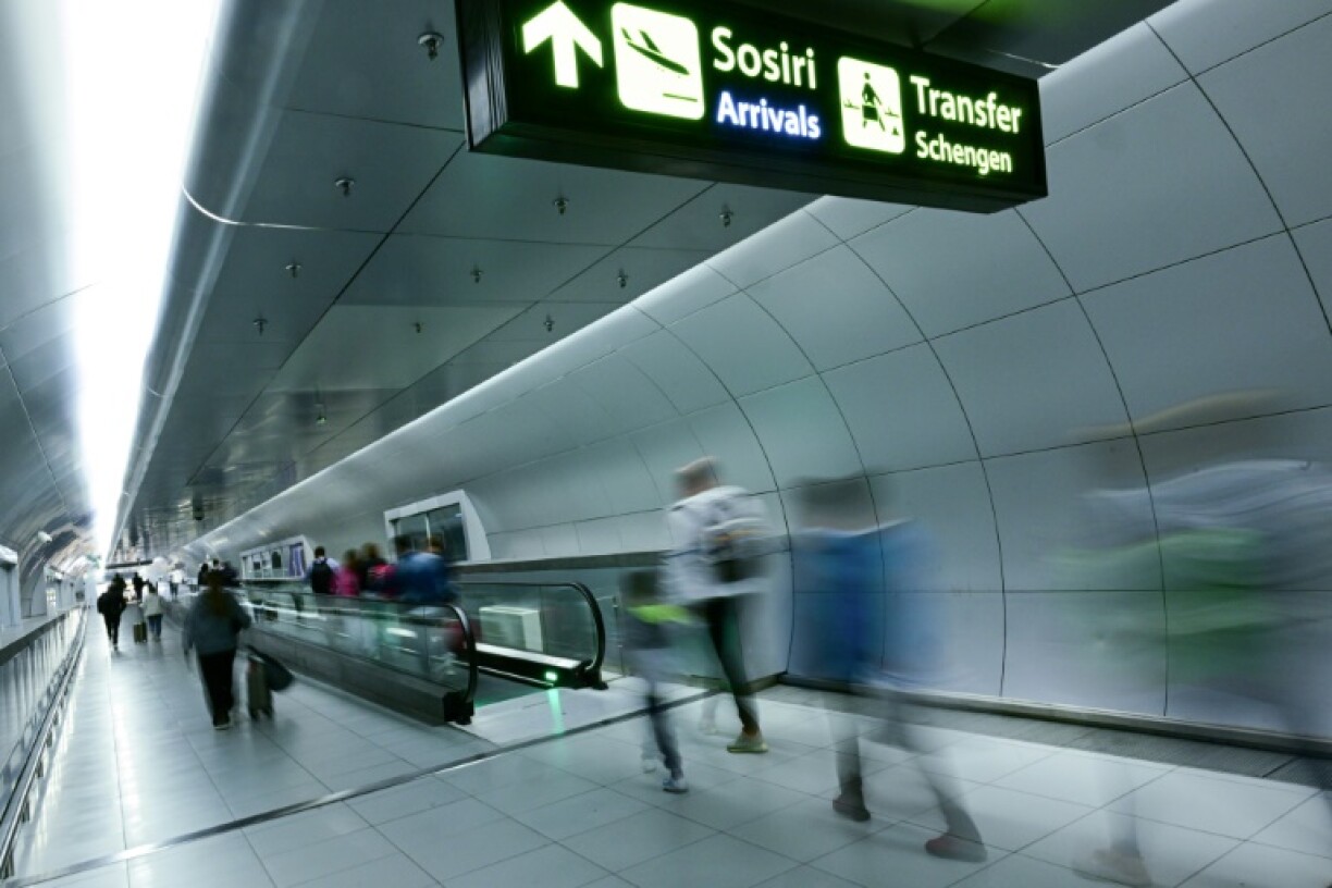 Des voyageurs passent sous les signaux, récemment installés, indiquant les transferts vers les pays situés dans l'espace Schengen, à l'aéroport international Otopeni en Roumanie, le 31 mars 2024