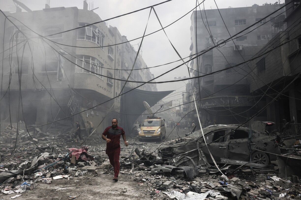 A Palestinian runs amidst the debris after an Israeli airstrike on buildings in the refugee camp of Jabalia in the Gaza Strip on October 9, 2023. Israel relentlessly pounded the Gaza Strip early Monday as fighting raged with Hamas around the Gaza Strip and the death toll from the war against the Palestinian militants surged above 1,100.