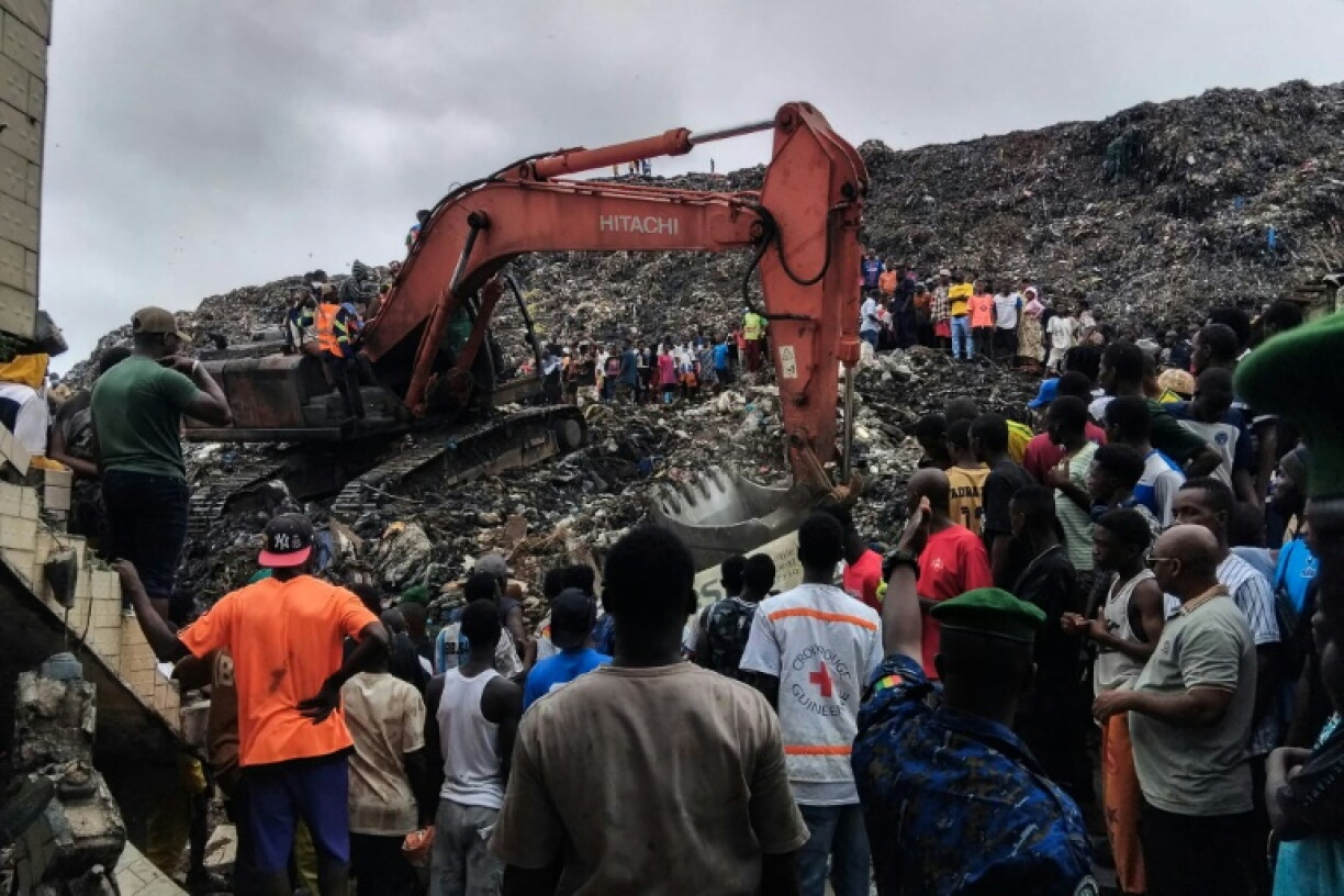 Une pelleteuse est utilisée pour rechercher des corps, après l'effondrement d'une décharge sur des habitations à Dar es salam dans la banlieue de Conakry, le 23 août 2026