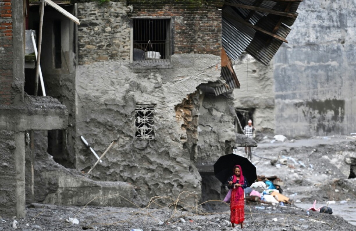 Une femme marche au milieu des bâtiments dévastés par la crue soudaine dans le district de Nuwakot, au Népal, le 1er septembre 2026