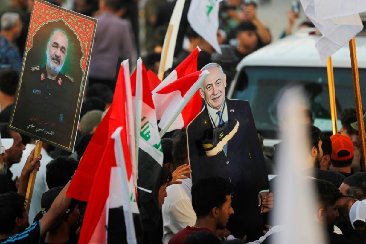 An Iraqi holds a picture of Major General Hossein Salami, head of the Iranian Revolutionary Guard, who was killed in an Israeli airstrike in Tehran, with another holding a cutout of Israeli Prime Minister Benjamin Netanyahu with a shoe around the neck during a protest in Baghdad