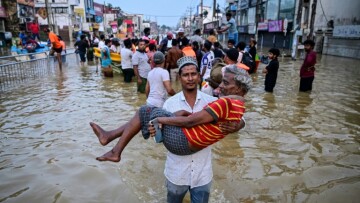 Un homme porte une personne âgée dans une rue inondée, le 30 novembre 2025 à Wellampitiya au Sri Lanka