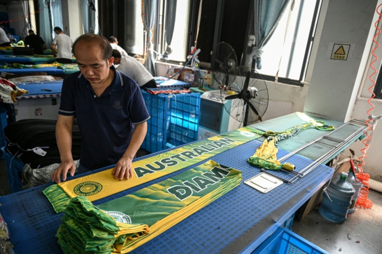 An employee irons scarves at a factory that produces hats and scarves in Yiwu, in eastern China's Zhejiang province on September 18, 2025