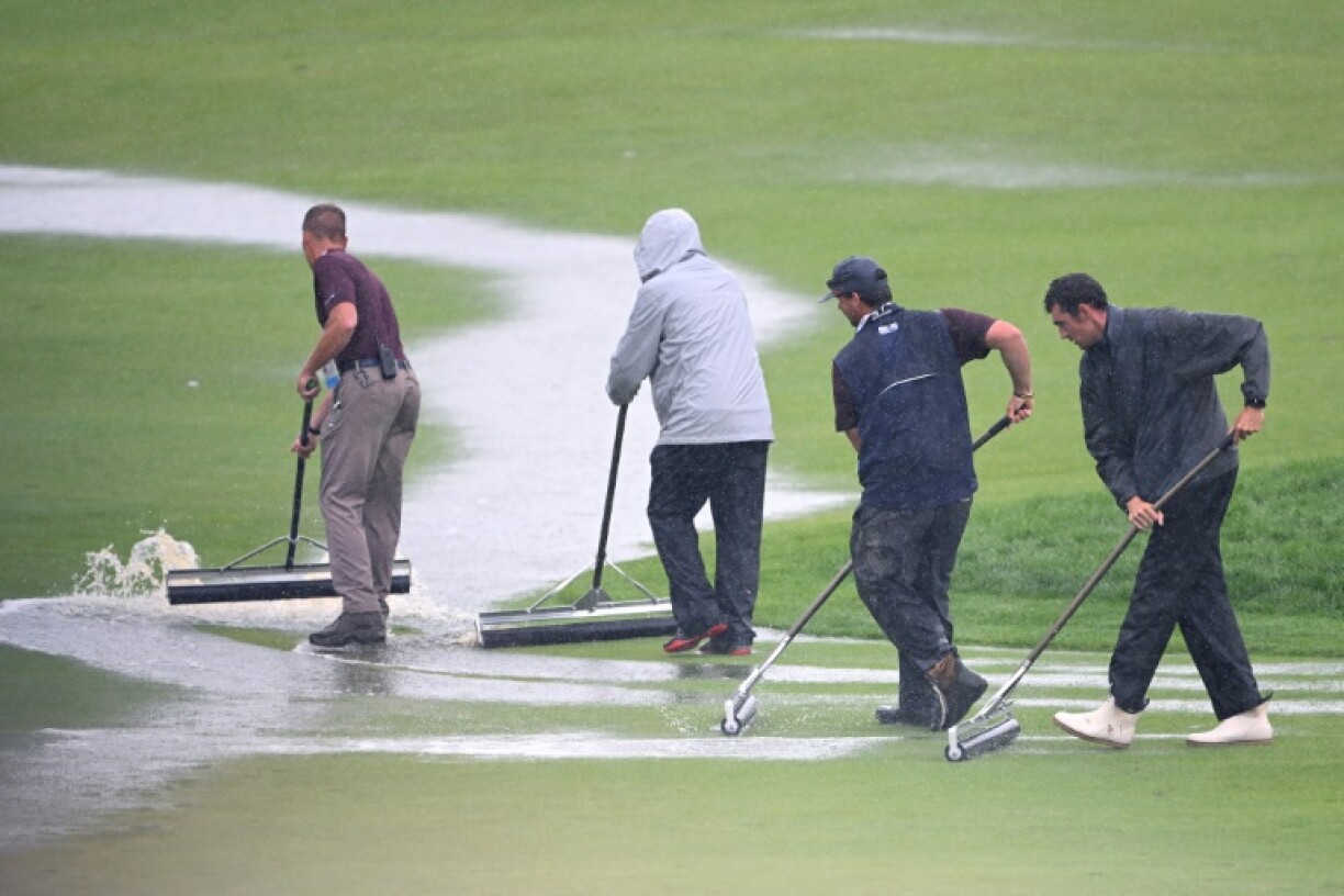 Groundskeepers at Oakmont brush water from the course on the 18th green during the storm-halted final round of the 125th US Open
