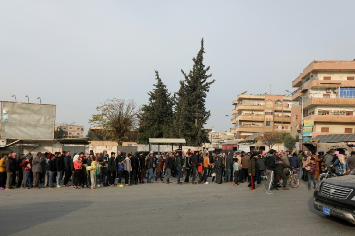People queue for bread distributed by rebels in Hama