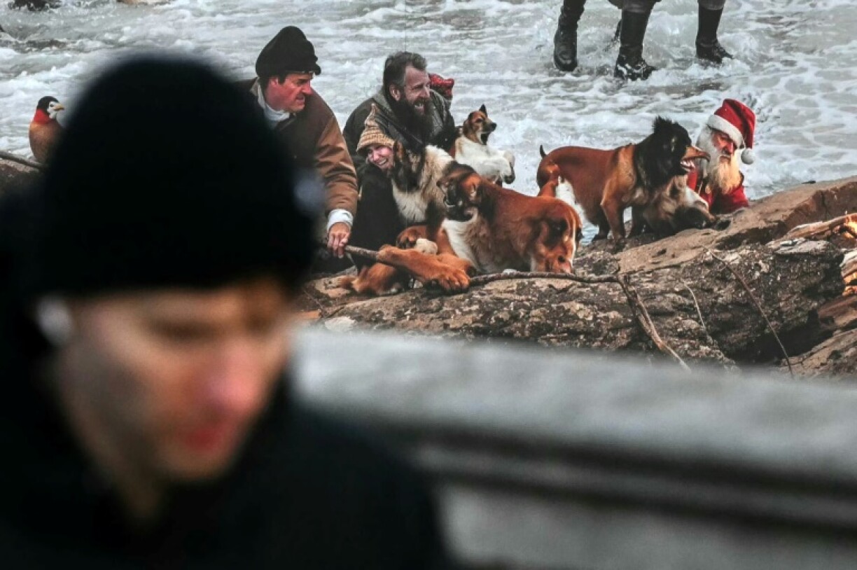 A Father Christmas figure is pictured looking pained in the water at the foot of a rock, his eyes shut and his beard half orange