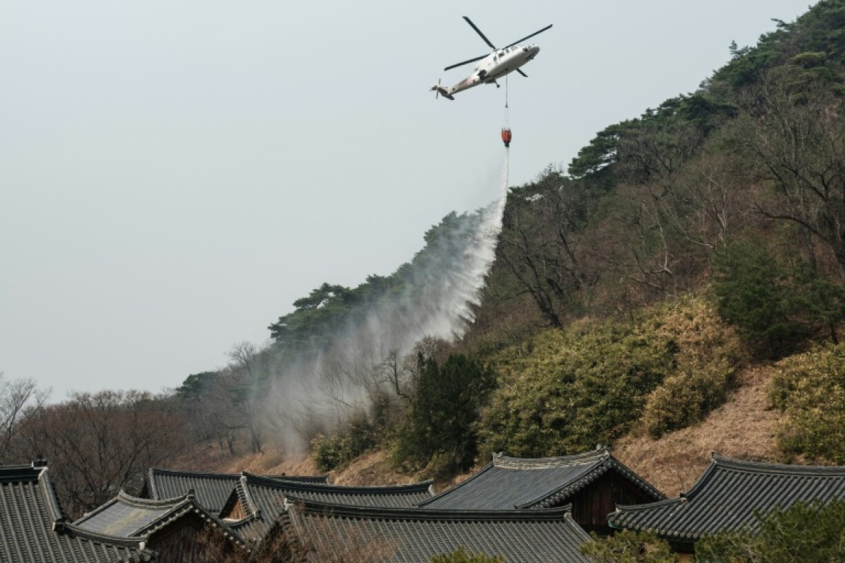 A helicopter drops water as a wildfire advances towards Gounsa Temple in Uiseong