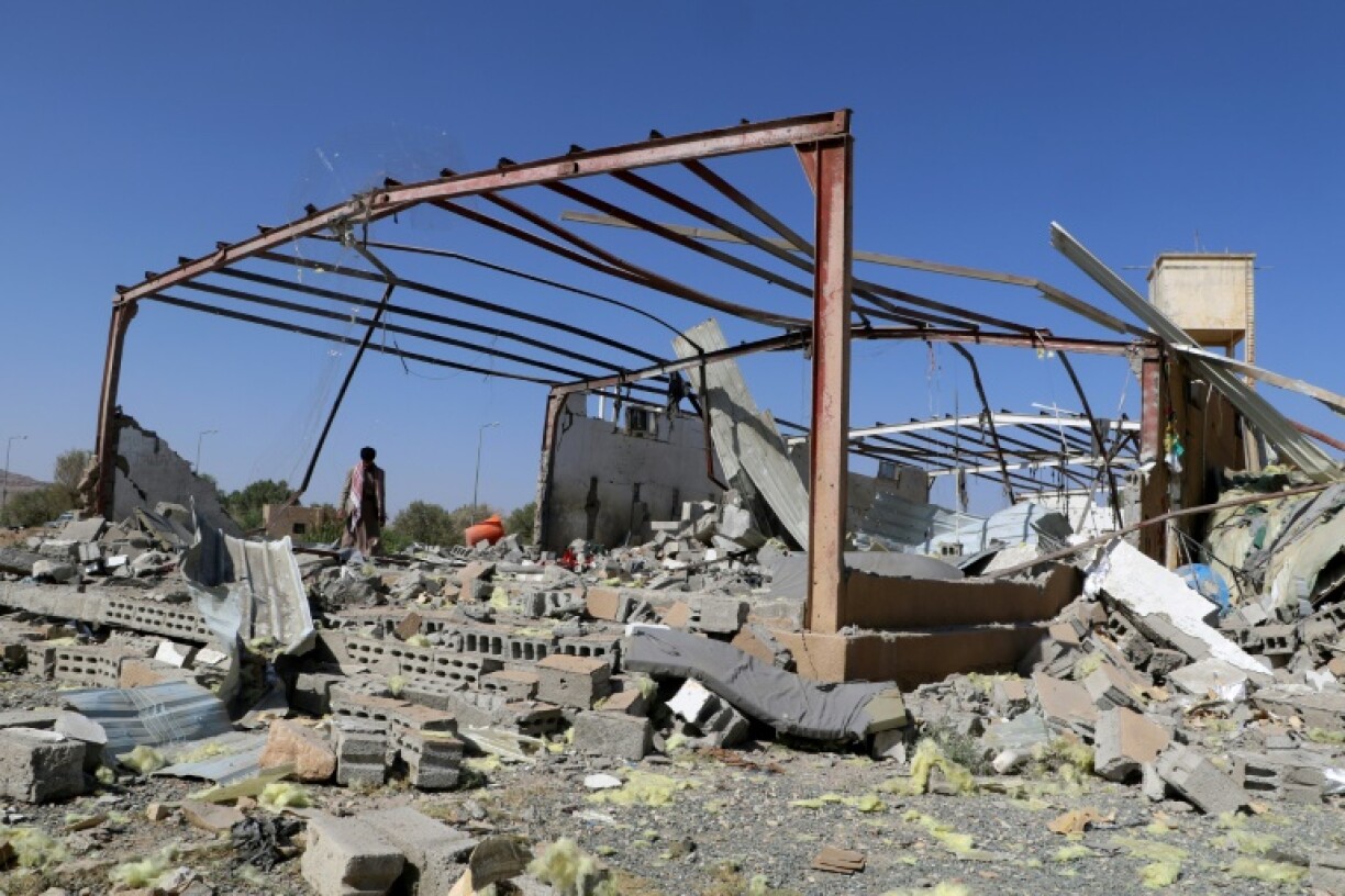 A man inspects the wreckage of a building destroyed in Yemen by a strike on a migrant centre attributed to the US