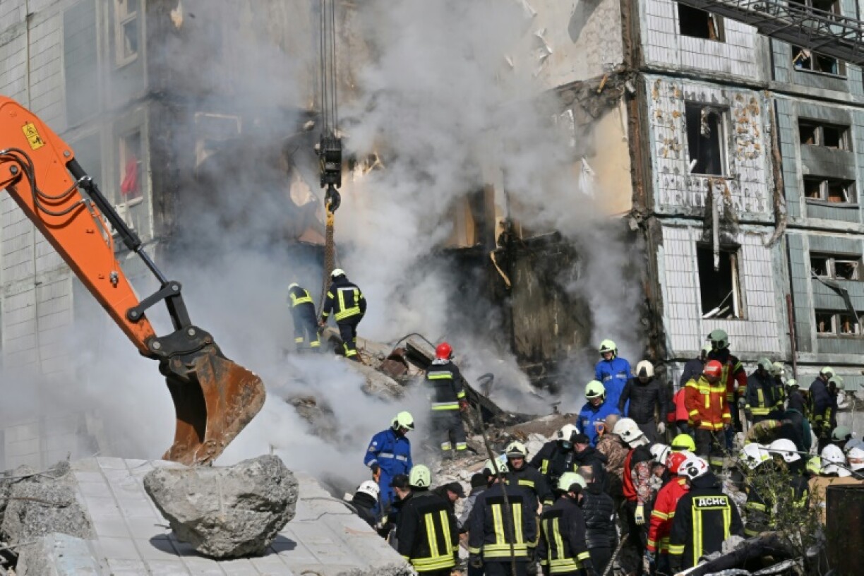 Des pompiers recherchent des survivants dans les décombres d'un immmeuble touché par une frappe russe, le 28 avril 2023 à Ouman, en Ukraine